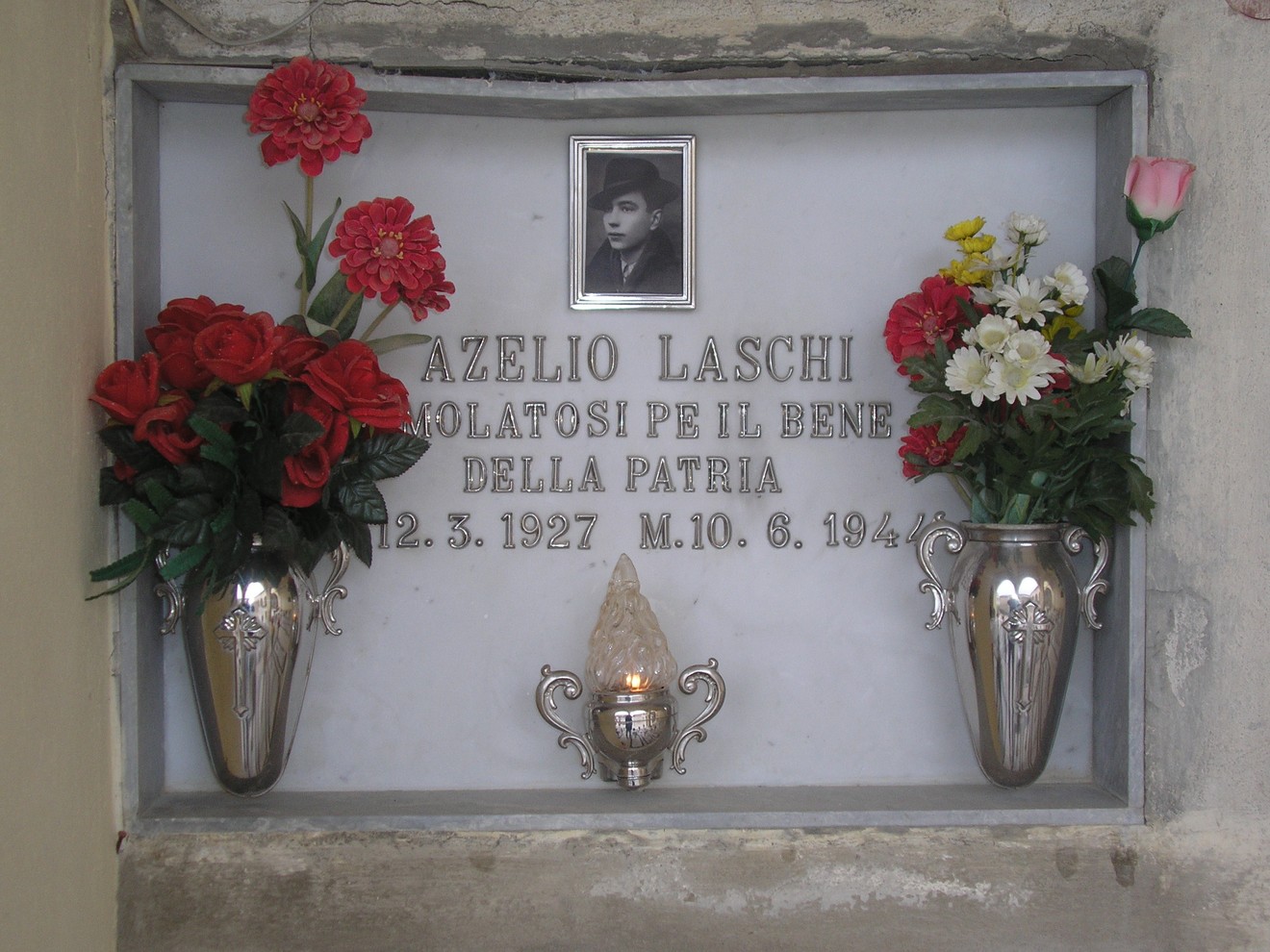 Sepolcro di Azelio Laschi, con fiori e lampade, simbolo di onore e memoria per un patriota.