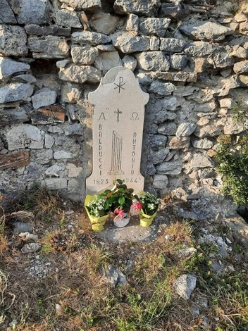 Targa commemorativa di Antonio Balducci, con decorazioni religiose, collocata tra le rocce.