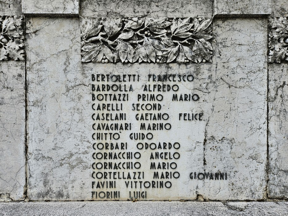 Monumento ai Caduti, con incisi nomi di soldati in memoria dei sacrifici. Ambiente sobrio e rispettoso.