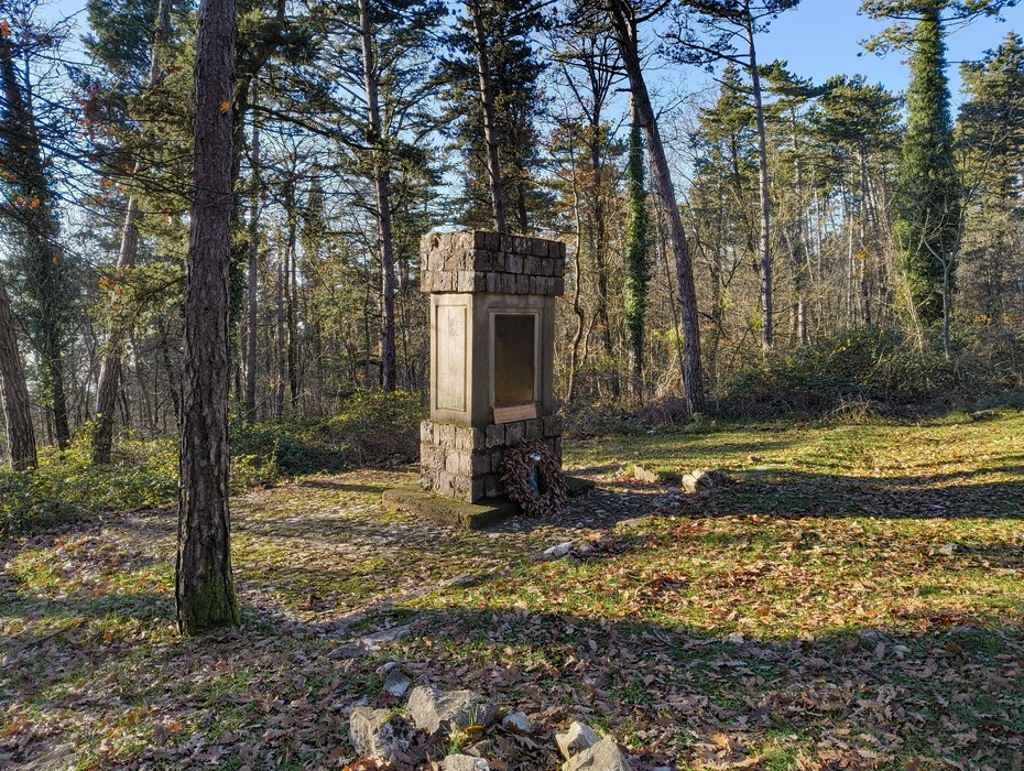 Monumento dedicato alla Battaglia della Fonte dei Seppi, immerso nel verde e circondato da alberi.