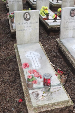 Tombe dei caduti per la Libertà, adornate con fiori e candele in un contesto di commemorazione.