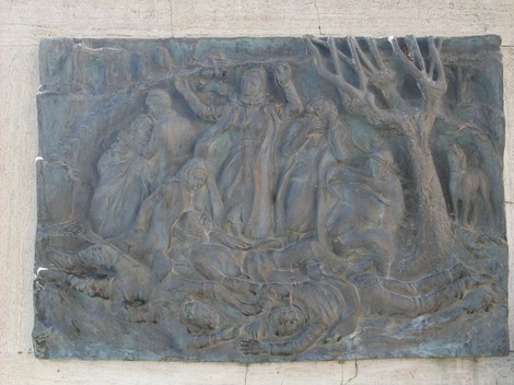 Bassorilievo commemorativo dedicato ai caduti della Guerra di Liberazione, evocante sofferenza e resistenza.