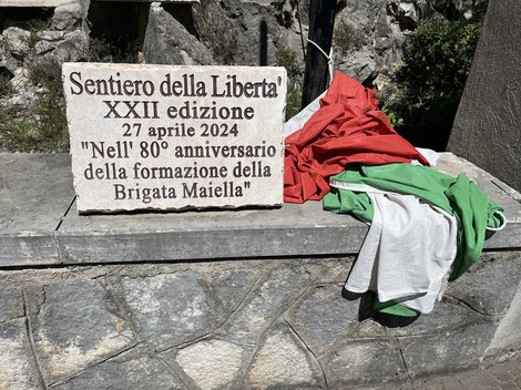 Il Sacrario della Brigata Maiella, con una targa commemorativa e bandiere tricolori, immerso nella natura.
