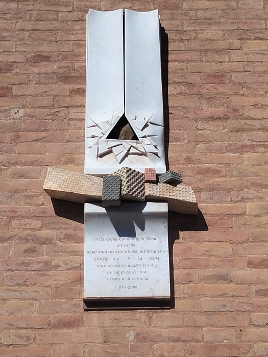 Lapide commemorativa dedicata alle sorelle Nissim, fissata su un muro di mattoni.