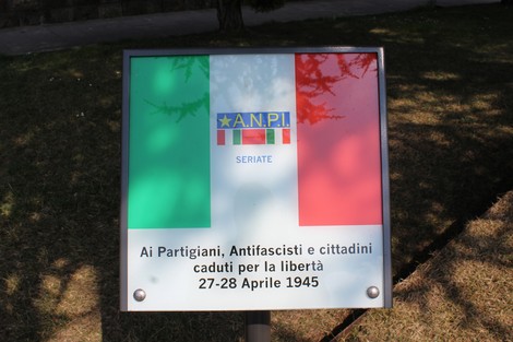 Monumento ai caduti partigiani con bandiera italiana, dedicato ai martiri per la libertà del 27-28 aprile 1945.