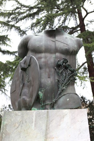 Monumento ad Anders, scultura di un torso con scudo e decorazioni, circondato da alberi.
