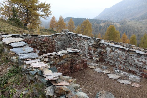 Ruderi del Vecchio rifugio dei Laghi Gemelli immersi nella natura, circondati da alberi e montagne.