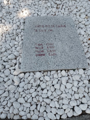 Monumento ai caduti per la Libertà, con una stele in pietra circondata da ghiaia bianca.