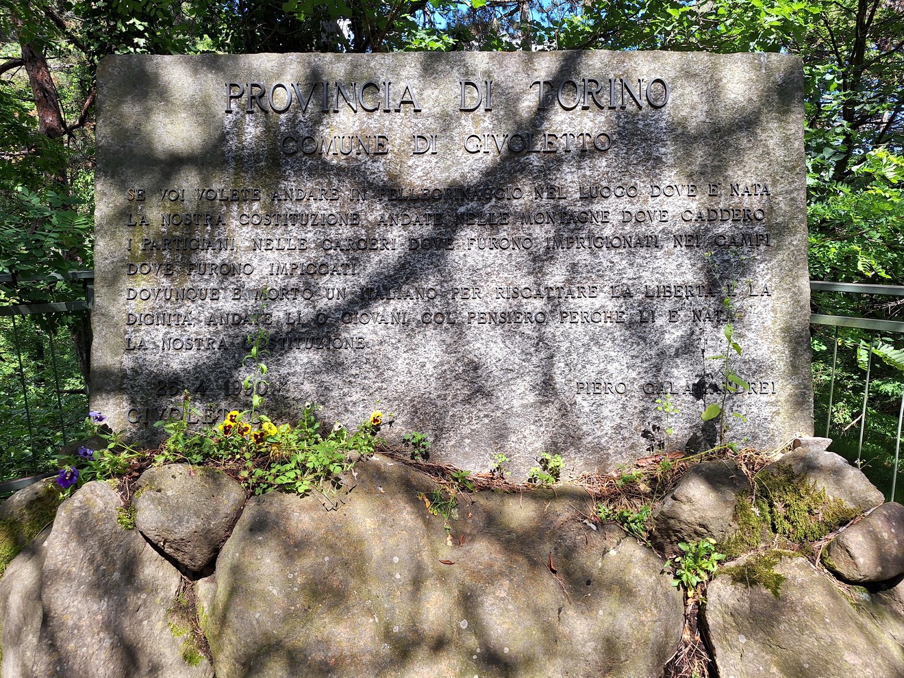 Lapide commemorativa alla Resistenza, situata in un ambiente verde e naturale.