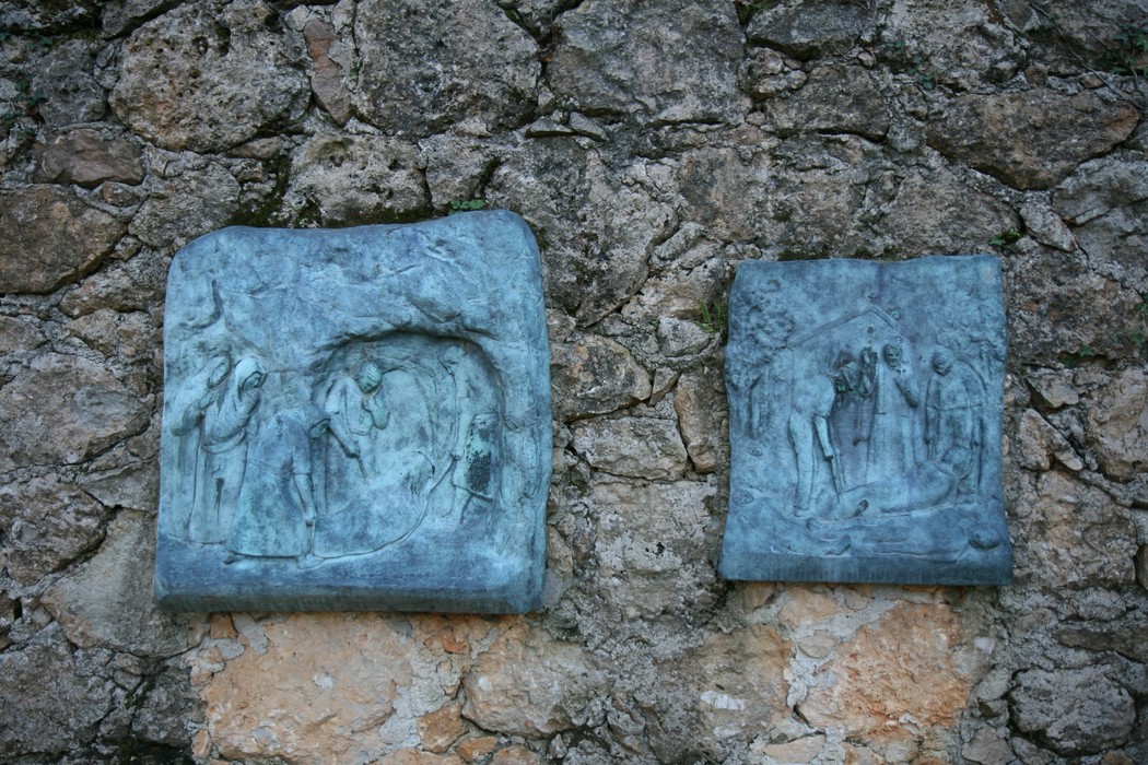 Rappresentazione della Via Crucis di Sant'Anna di Stazzema, con rilievi su muro di pietra.