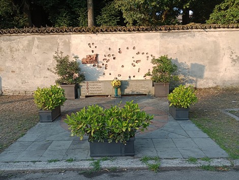 Monumento ai caduti del 18 marzo 1945, circondato da piante e in un contesto tranquillo.