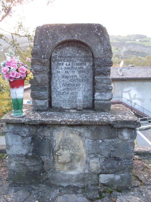 Monumento commemorativo dedicato a Pinotti, Gennari, Sensioni e Schianchi, con decorazioni floreali.