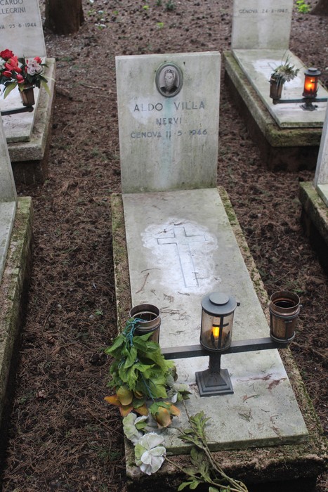Tombe perpetue dedicate ai caduti, con fiori e candele, in un ambiente naturale sereno.