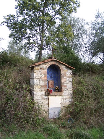 Tabernacolo di cucina in un ambiente naturale, con decorazioni floreali e sfondo di vegetazione.