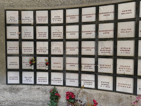 Monumento Ossario con nomi di caduti partigiani, commemorato da fiori e un'atmosfera di ricordo.