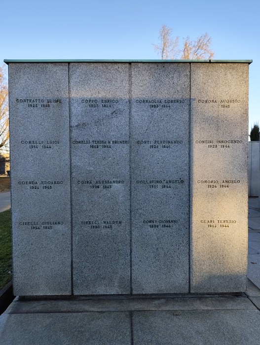 Monumento commemorativo con nomi incisi, dedicato ai caduti di "Campo della Gloria". Atmosfera serena e riflessiva.