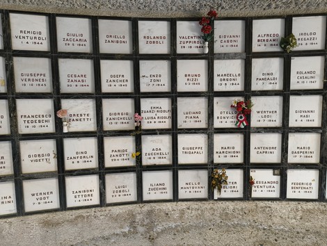 Monumento Ossario dedicato ai caduti partigiani, con lastre commemorative e fiori in ricordo.