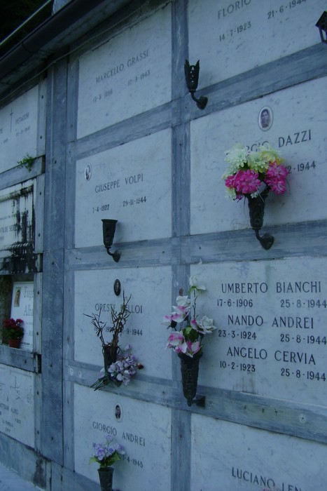 Sepolcri commemorativi dedicati ai caduti per la libertà, adornati con fiori e ricordi.