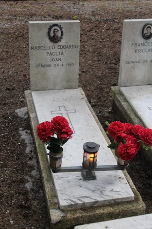 Tombe con fiori rossi e candele, dedicate ai caduti per la Libertà, in un cimitero tranquillo.