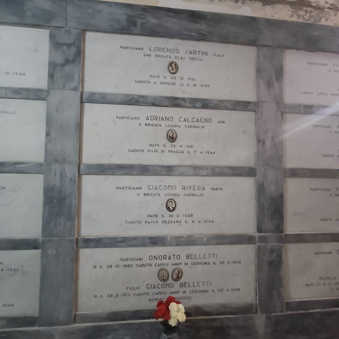 Loculi marmorei con targhe a parete, foto dei caduti e fiori deposti davanti ad alcune lapidi.