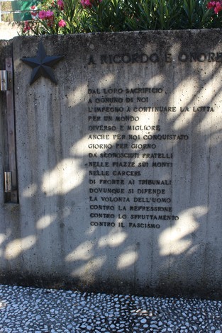 Monumento alla Resistenza, con iscrizioni commemorative su un muro in cemento e una stella sopra.