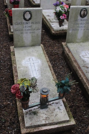 Tombe decorate con fiori in memoria dei caduti per la Libertà, con croce e lumino attivo.
