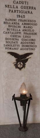 Cappella dei caduti con iscrizioni commemorative e lampada votiva, simbolo di rispetto e memoria.