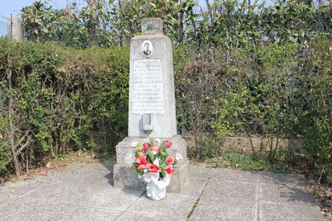 Cippo commemorativo a Gavioli con fiori decorativi, immerso nel verde.