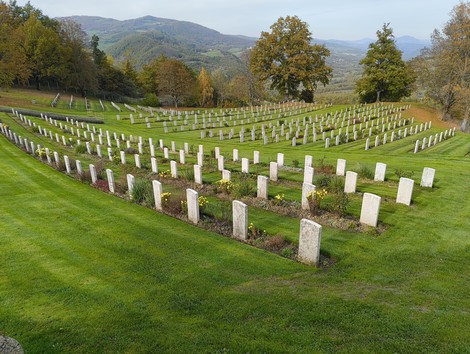 Cimitero di guerra sudafricano, con campi verdi e tombe in fila, immerso nella quiete della natura.
