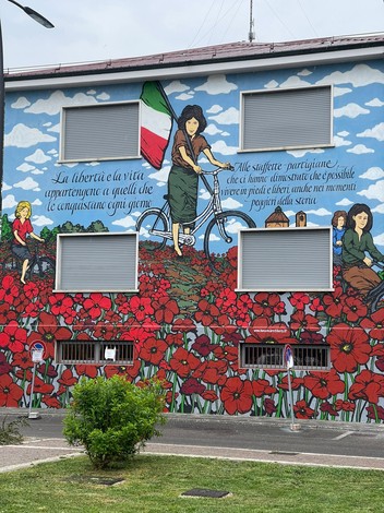 Murale celebrativo delle staffette partigiane, con figure femminili in un paesaggio fiorito, simbolo di libertà e resistenza.