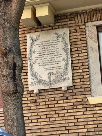 Lapide commemorativa a Fano, con iscrizioni storiche su un muro di mattoni.