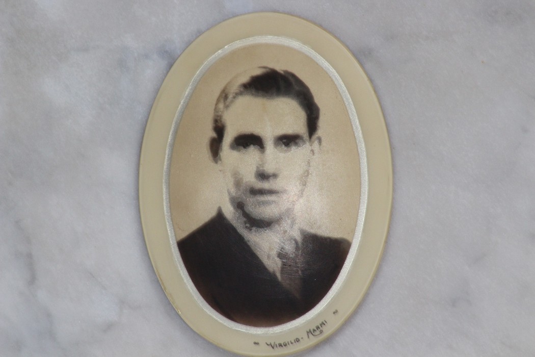 Ritratto di un giovane uomo, incastonato in una cornice ovale, in memoria dei caduti per la Liberazione.
