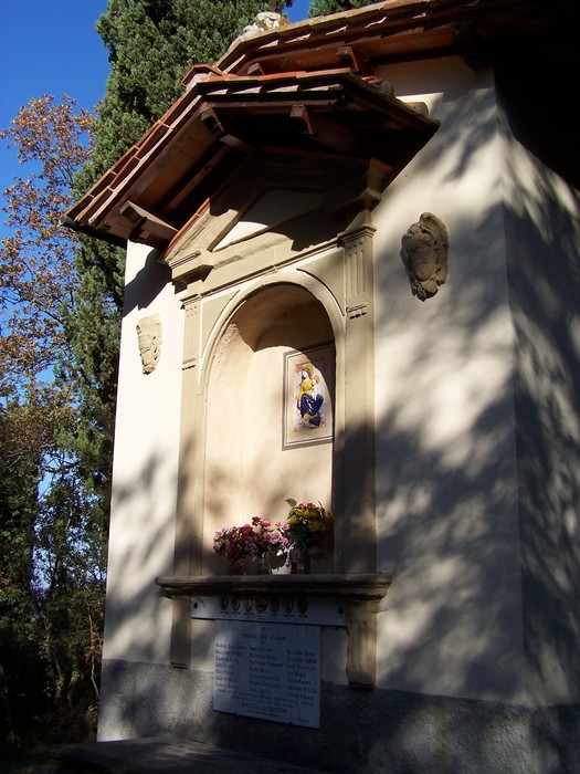Tabernacolo di Montefiano con architettura semplice e decorazioni floreali, immerso nella natura.