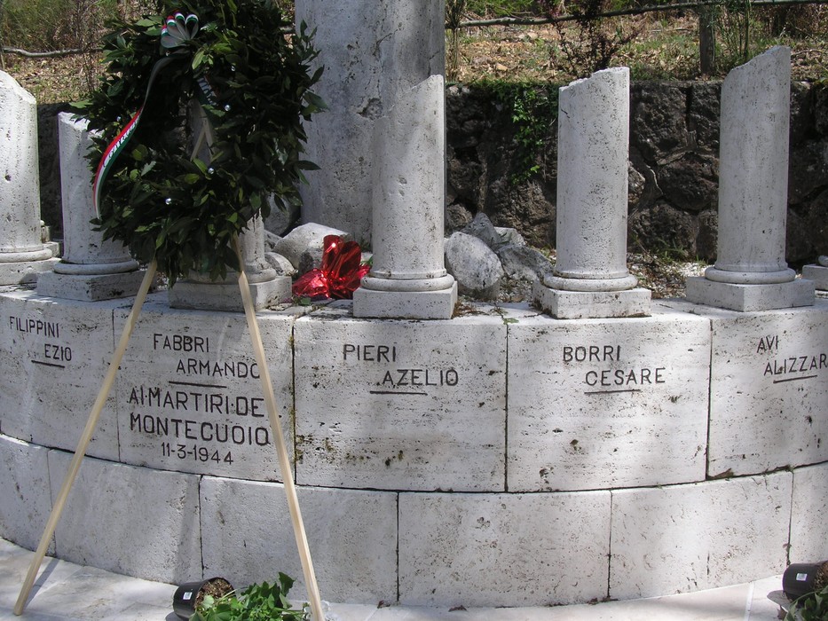 Monumento commemorativo ai caduti di Scalvaia, con nomi incisi su monumenti di pietra e una corona d'alloro.