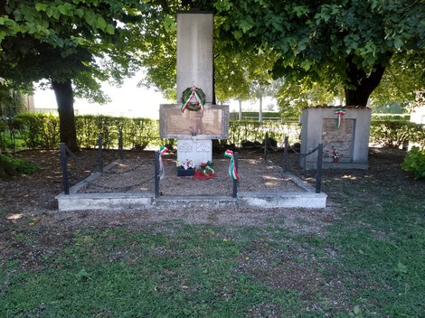 Monumento dedicato ai caduti per la Libertà, circondato da alberi e decorazioni tricolore.