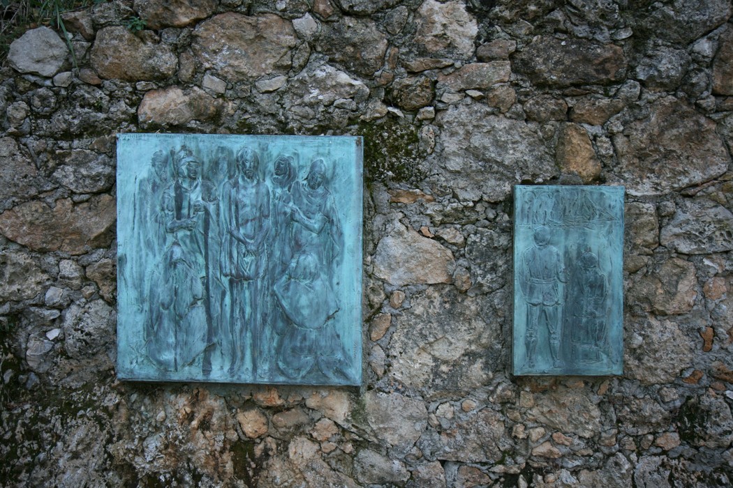 Rappresentazione bronzea della Via Crucis, situata a Sant'Anna di Stazzema, immersa in un contesto di pietra.