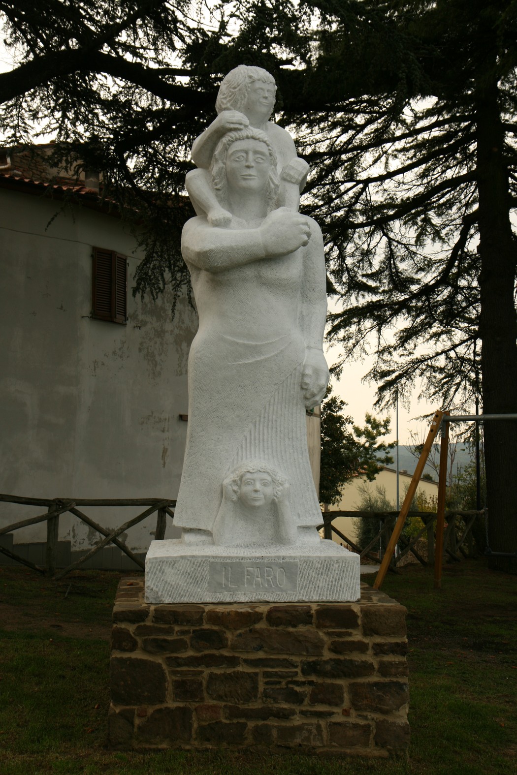 Monumento in pietra dedicato ai caduti, raffigura una madre con un bambino in un gesto di memoriale e pietà.