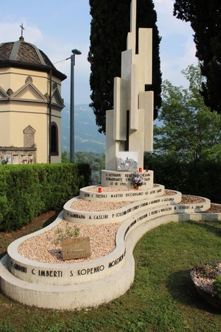 Sacrario alla 53a Brigata Garibaldi, un monumento commemorativo tra vegetazione e un cielo sereno.