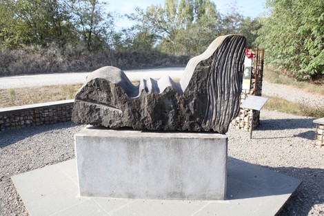 Monumento ai Martiri del Panaro, scultura in pietra posta su un basamento, immerso nella natura circostante.
