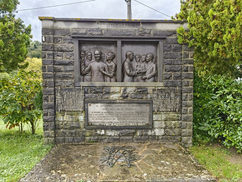 Monumento commemorativo dedicato a Comini, con rilievi e dediche in memoria della sua figura storica.