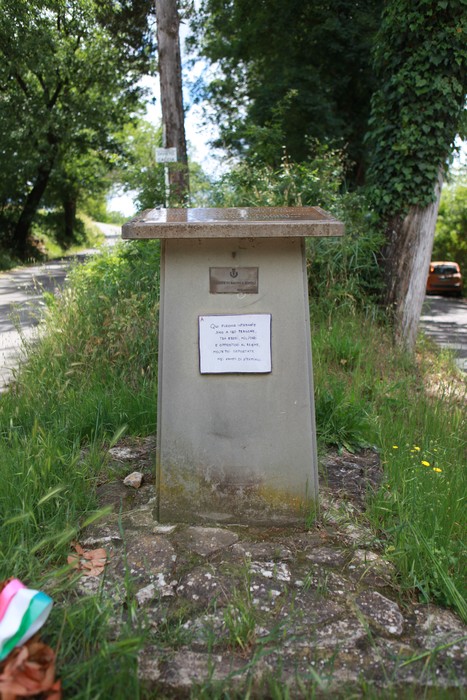 Cippo di Villa La Selva, monumento in pietra circondato da vegetazione lungo una strada.