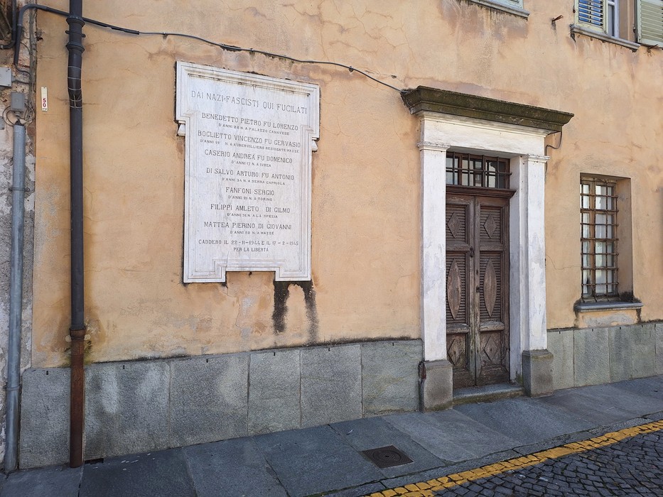 Lapide commemorativa dedicata ai VII Martiri, affissa su un muro di edificio storico.