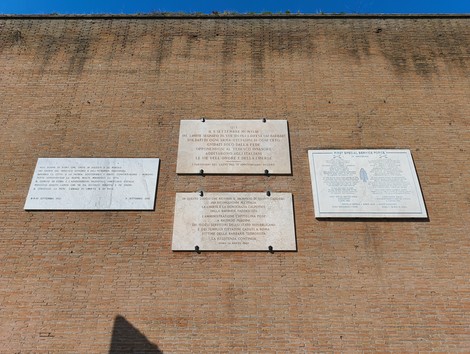 Lapidi storiche su una parete di mattoni a Porta San Paolo, con testo commemorativo e di riflessione.