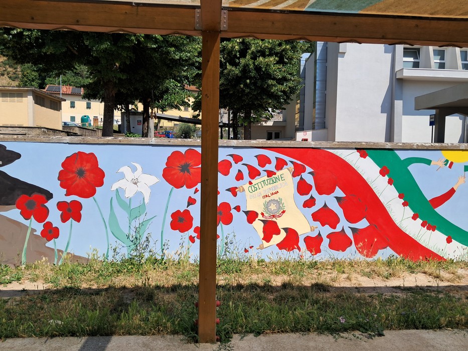 Murale commemorativo con fiori rossi e simboli, dedicato all'80° anniversario della Liberazione di San Piero.