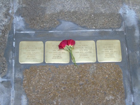 Pietre d'inciampo commemorative dedicate alla famiglia Melli, decorate con fiori rossi.