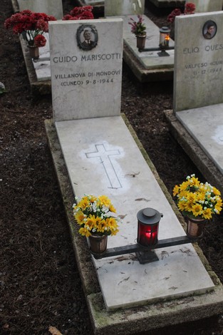Tombe decorate con fiori e candele in memoria dei caduti per la Libertà, in un luogo di commemorazione.