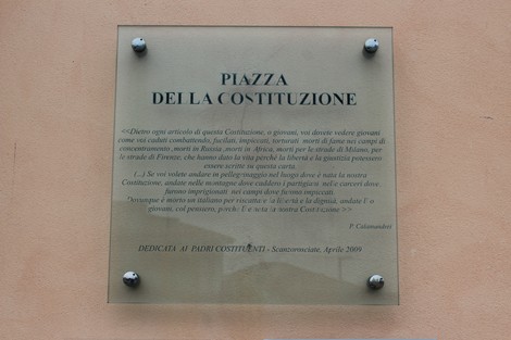 Piazza della Costituzione, spazio pubblico con placca commemorativa e atmosfere storiche e architettoniche.