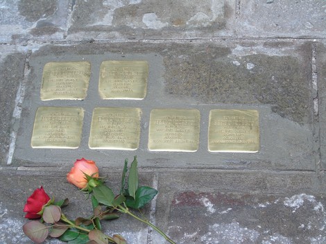 Pietre d'inciampo dedicate alla famiglia Dina - Todesco, collocate nel selciato, con una rosa accanto.