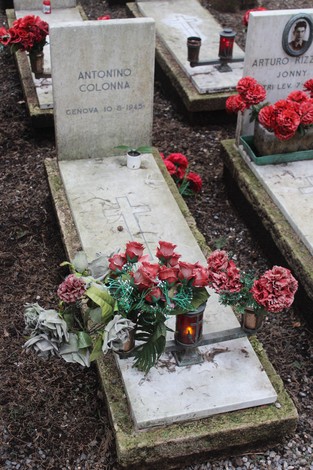 Tombe commemorative decorate con fiori rossi e lampade, dedicate ai caduti per la Libertà.