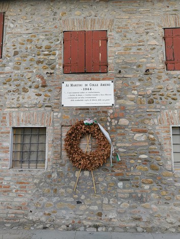 Lapide commemorativa ai martiri di Colle Ameno del 1944, con una corona di fiori.